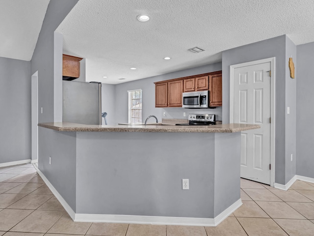 kitchen with kitchen peninsula, appliances with stainless steel finishes, and light tile patterned floors