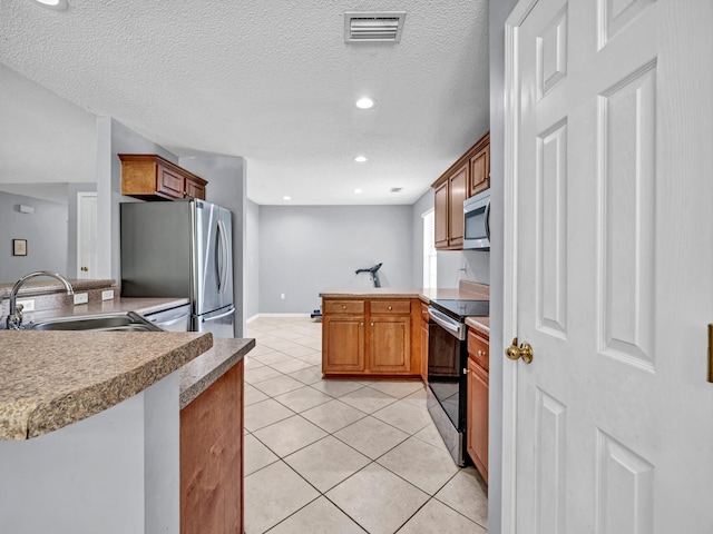 kitchen with light tile patterned flooring, a textured ceiling, kitchen peninsula, stainless steel appliances, and sink