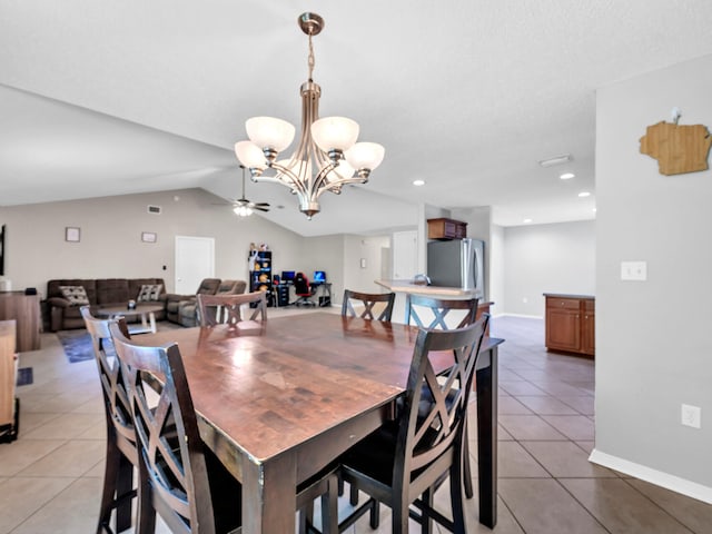 tiled dining room with ceiling fan with notable chandelier and lofted ceiling