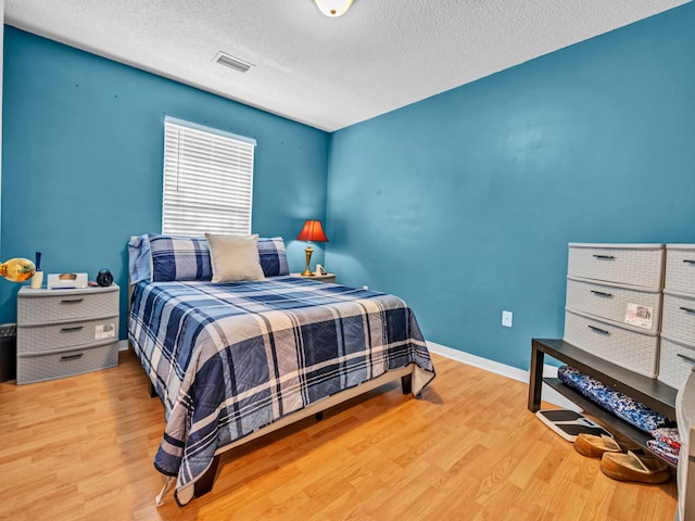 bedroom featuring light wood-type flooring and a textured ceiling