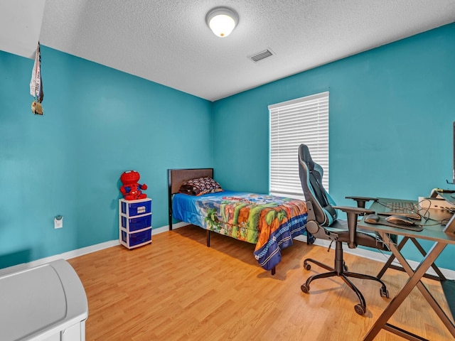 bedroom featuring a textured ceiling and light hardwood / wood-style flooring