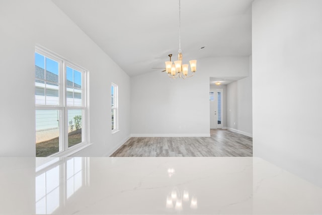 unfurnished room with hardwood / wood-style flooring, lofted ceiling, and a chandelier