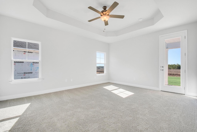 carpeted empty room featuring a raised ceiling and ceiling fan