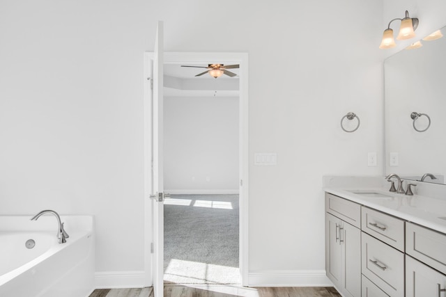 bathroom with vanity, hardwood / wood-style flooring, a tub, and ceiling fan