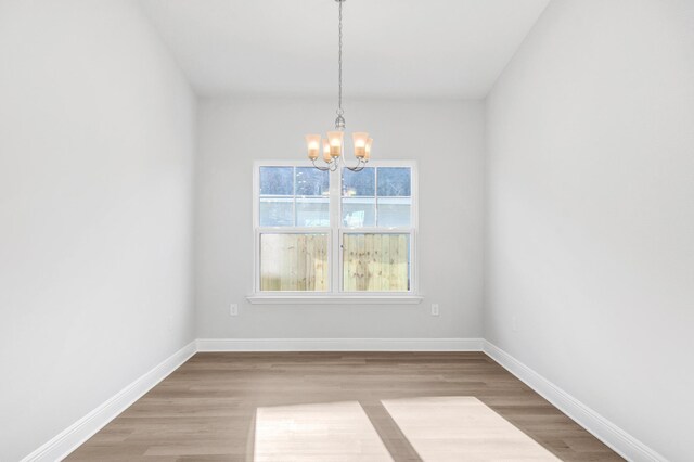 unfurnished room featuring a notable chandelier and hardwood / wood-style floors