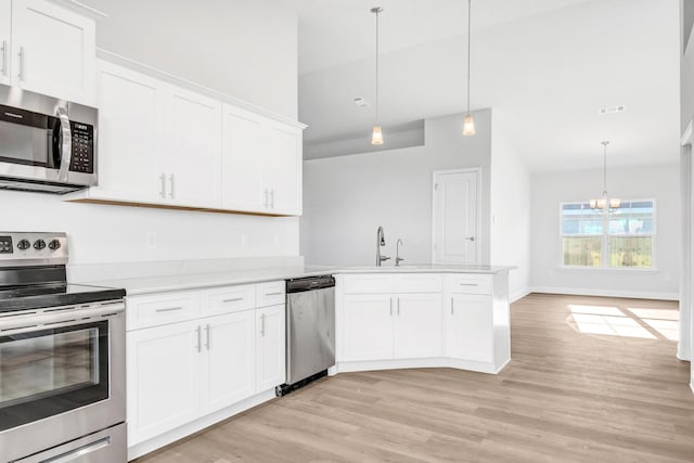 kitchen featuring light wood-type flooring, kitchen peninsula, decorative light fixtures, appliances with stainless steel finishes, and white cabinets