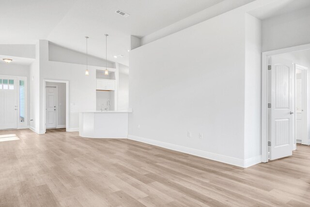 unfurnished living room with light hardwood / wood-style floors and high vaulted ceiling