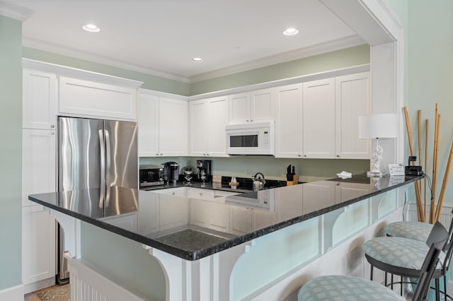 kitchen featuring dark stone countertops, white cabinetry, crown molding, and stainless steel appliances
