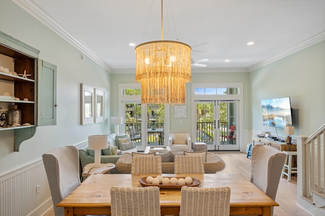 dining area with a chandelier, crown molding, light wood-type flooring, and french doors
