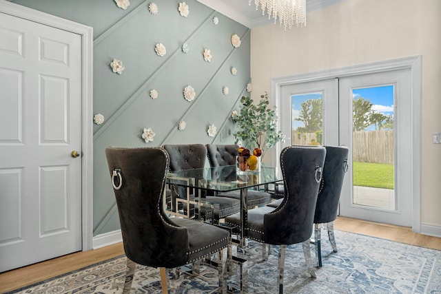 dining area with light hardwood / wood-style floors, a notable chandelier, french doors, and ornamental molding