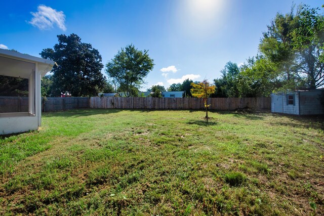 view of yard with an outbuilding, a fenced backyard, and a storage unit