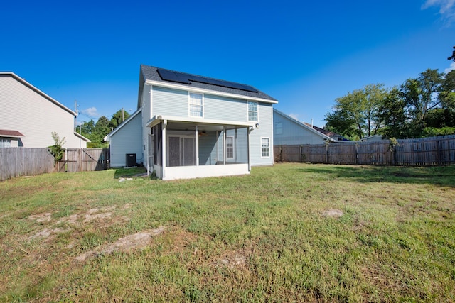 back of property featuring solar panels, a yard, and a sunroom