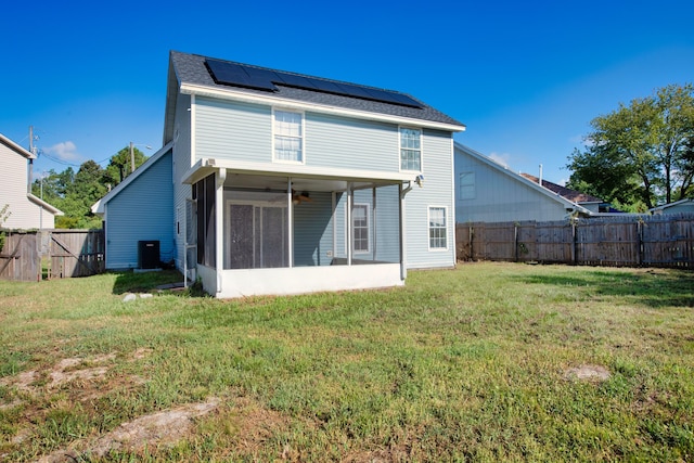 rear view of house featuring central air condition unit, a sunroom, a yard, and solar panels