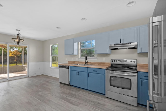 kitchen featuring under cabinet range hood, appliances with stainless steel finishes, wooden counters, and a sink