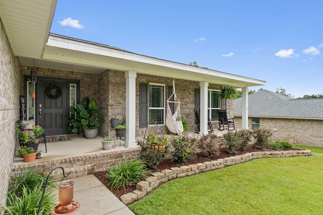 entrance to property with covered porch and a lawn