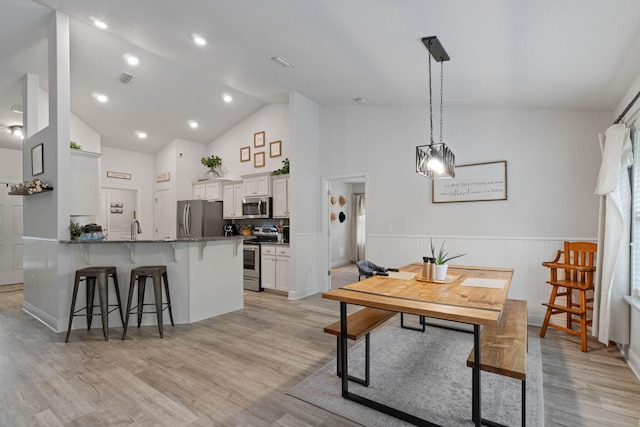 kitchen featuring high vaulted ceiling, stainless steel appliances, kitchen peninsula, and light hardwood / wood-style floors