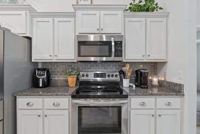 kitchen featuring appliances with stainless steel finishes, tasteful backsplash, dark stone counters, and white cabinetry