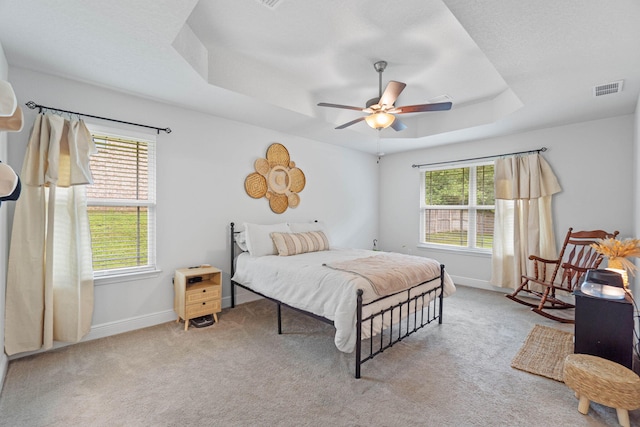 bedroom featuring ceiling fan, a raised ceiling, and light colored carpet