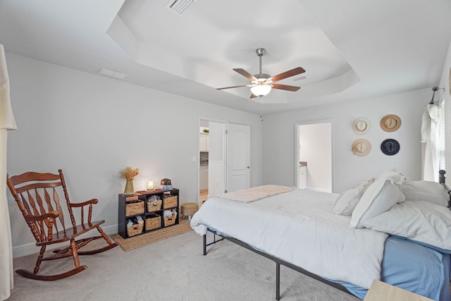 carpeted bedroom featuring connected bathroom, ceiling fan, and a raised ceiling