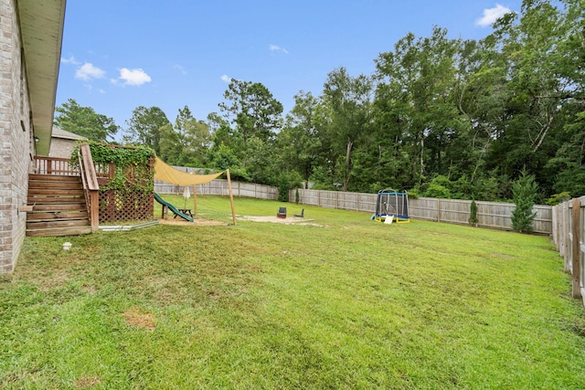 view of yard with a trampoline and a wooden deck