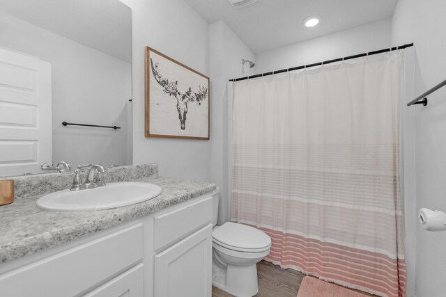 bathroom with hardwood / wood-style floors, toilet, and vanity