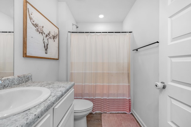 bathroom with hardwood / wood-style flooring, toilet, and vanity