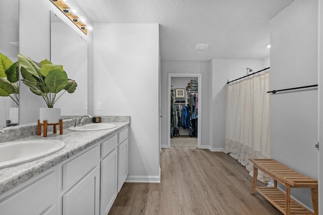 bathroom with dual vanity, a textured ceiling, and hardwood / wood-style floors