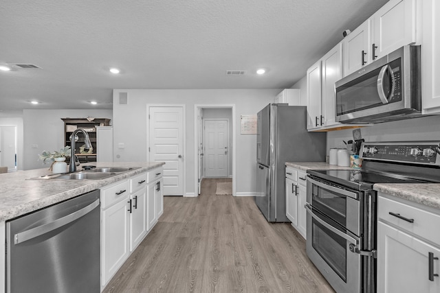 kitchen featuring sink, light hardwood / wood-style flooring, white cabinetry, and stainless steel appliances