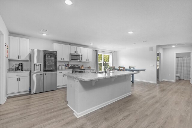 6537 Torrey Pnes, Laurel Hill, FL 32567 - kitchen with light wood-type flooring, stainless steel appliances, a sink, a kitchen island, and white cabinets