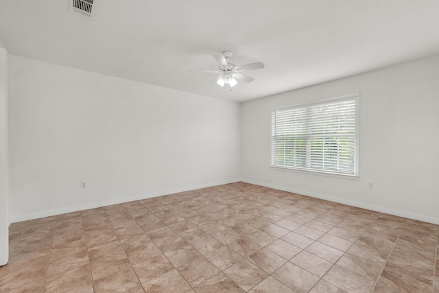 tiled spare room with ceiling fan