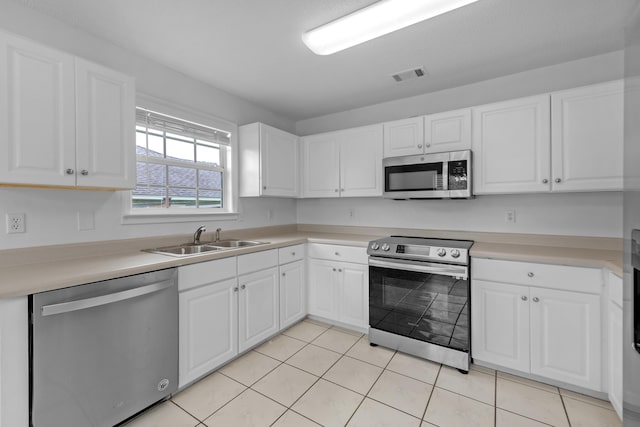 kitchen with light tile patterned flooring, sink, stainless steel appliances, and white cabinets