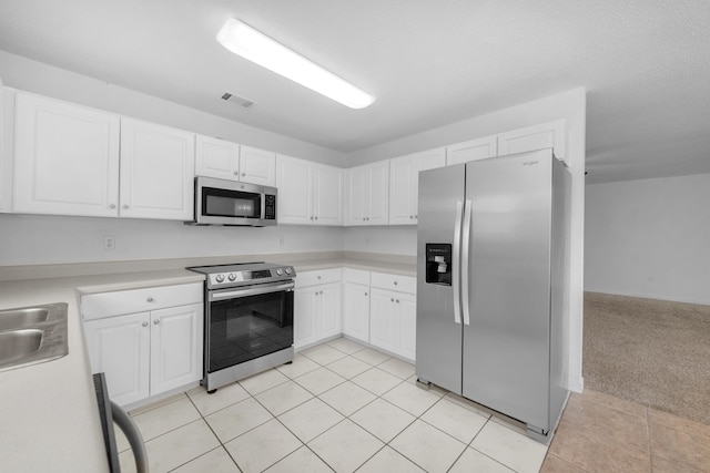 kitchen with light carpet, white cabinetry, and stainless steel appliances