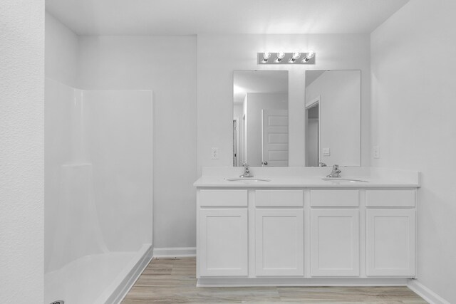 bathroom with hardwood / wood-style flooring, walk in shower, and double vanity