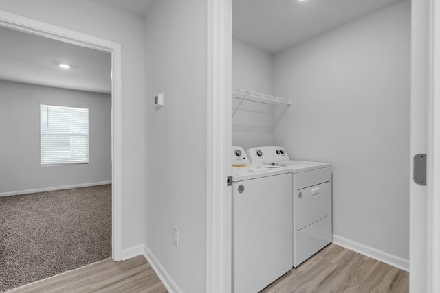 laundry room with washer and dryer and light wood-type flooring