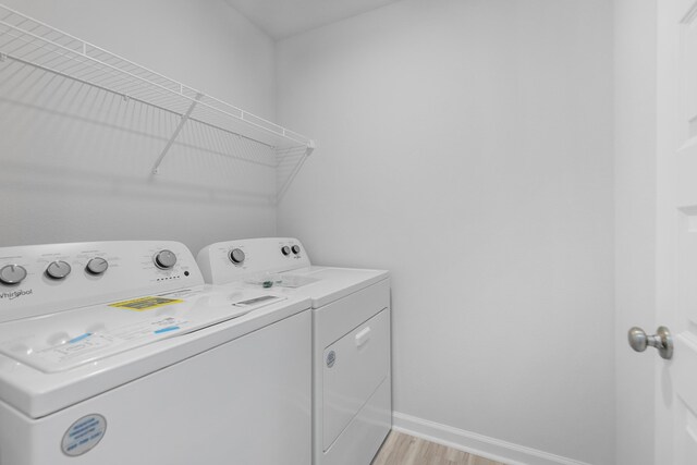 clothes washing area with light wood-type flooring and washer and dryer