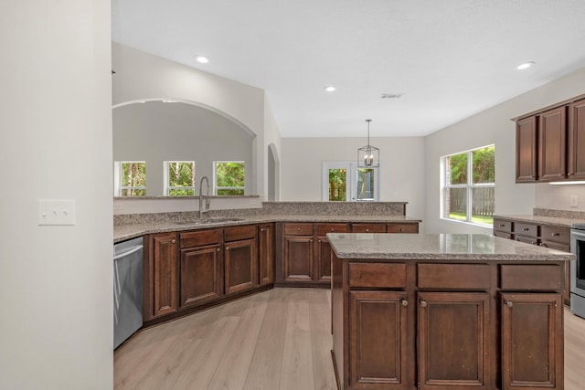 kitchen with visible vents, appliances with stainless steel finishes, a center island, light stone countertops, and a sink