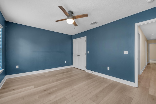 empty room featuring a textured ceiling, light hardwood / wood-style flooring, and ceiling fan