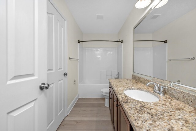 full bathroom with toilet, vanity,  shower combination, and hardwood / wood-style floors