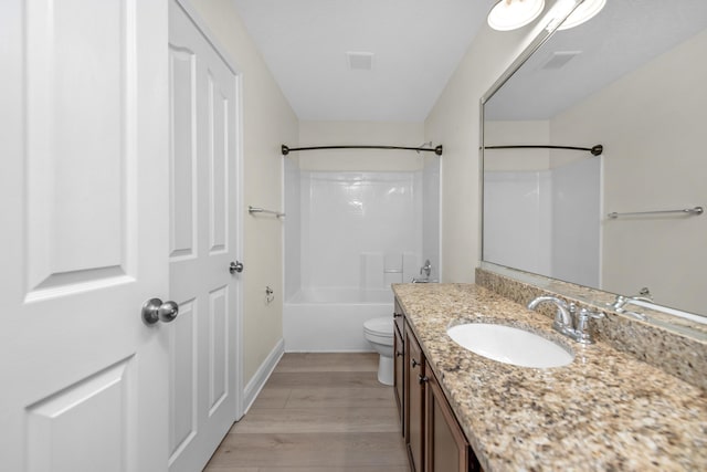 full bath with baseboards, toilet, shower / tub combination, wood finished floors, and vanity