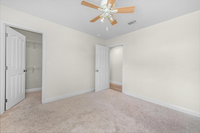 unfurnished bedroom with light carpet, visible vents, baseboards, and a spacious closet