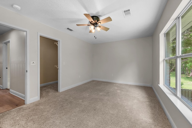 carpeted spare room with a ceiling fan, visible vents, and baseboards