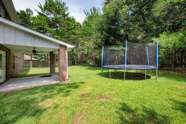 view of yard with a trampoline, a fenced backyard, and a patio