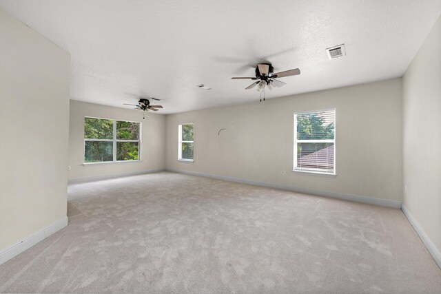 carpeted empty room featuring a healthy amount of sunlight and ceiling fan