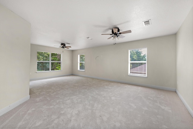 spare room featuring visible vents, a healthy amount of sunlight, and light carpet