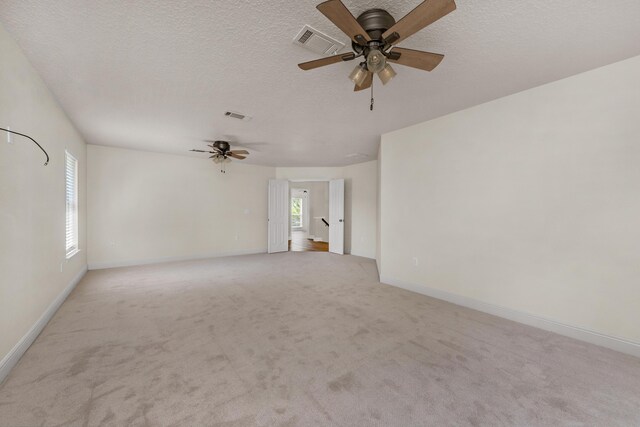 empty room with light carpet, ceiling fan, and a textured ceiling