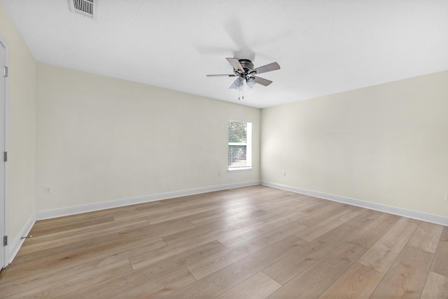 spare room with light wood-style floors, visible vents, ceiling fan, and baseboards