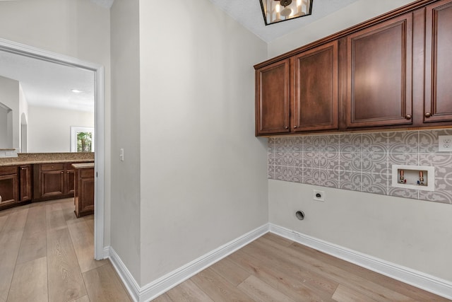 laundry room with hookup for an electric dryer, washer hookup, baseboards, light wood-style floors, and cabinet space