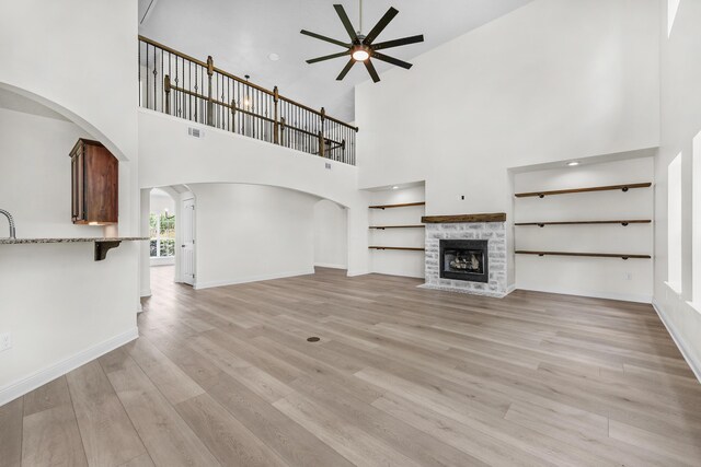 unfurnished living room with light hardwood / wood-style floors, ceiling fan, and a high ceiling