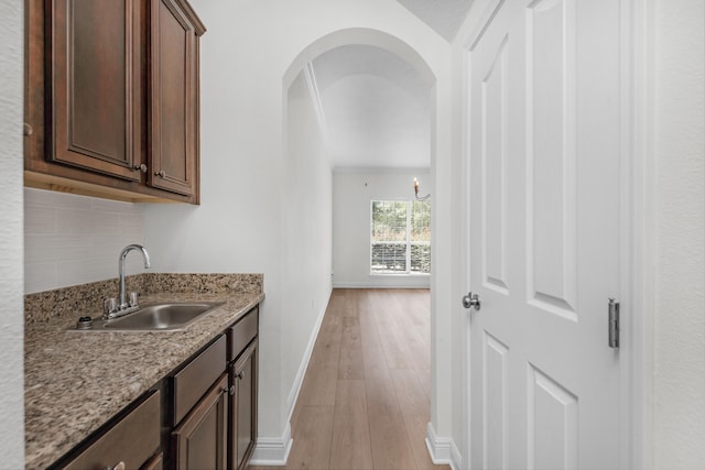 interior space featuring backsplash, sink, light stone countertops, and light hardwood / wood-style floors