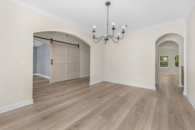 unfurnished room with a chandelier, ornamental molding, light hardwood / wood-style flooring, and a barn door